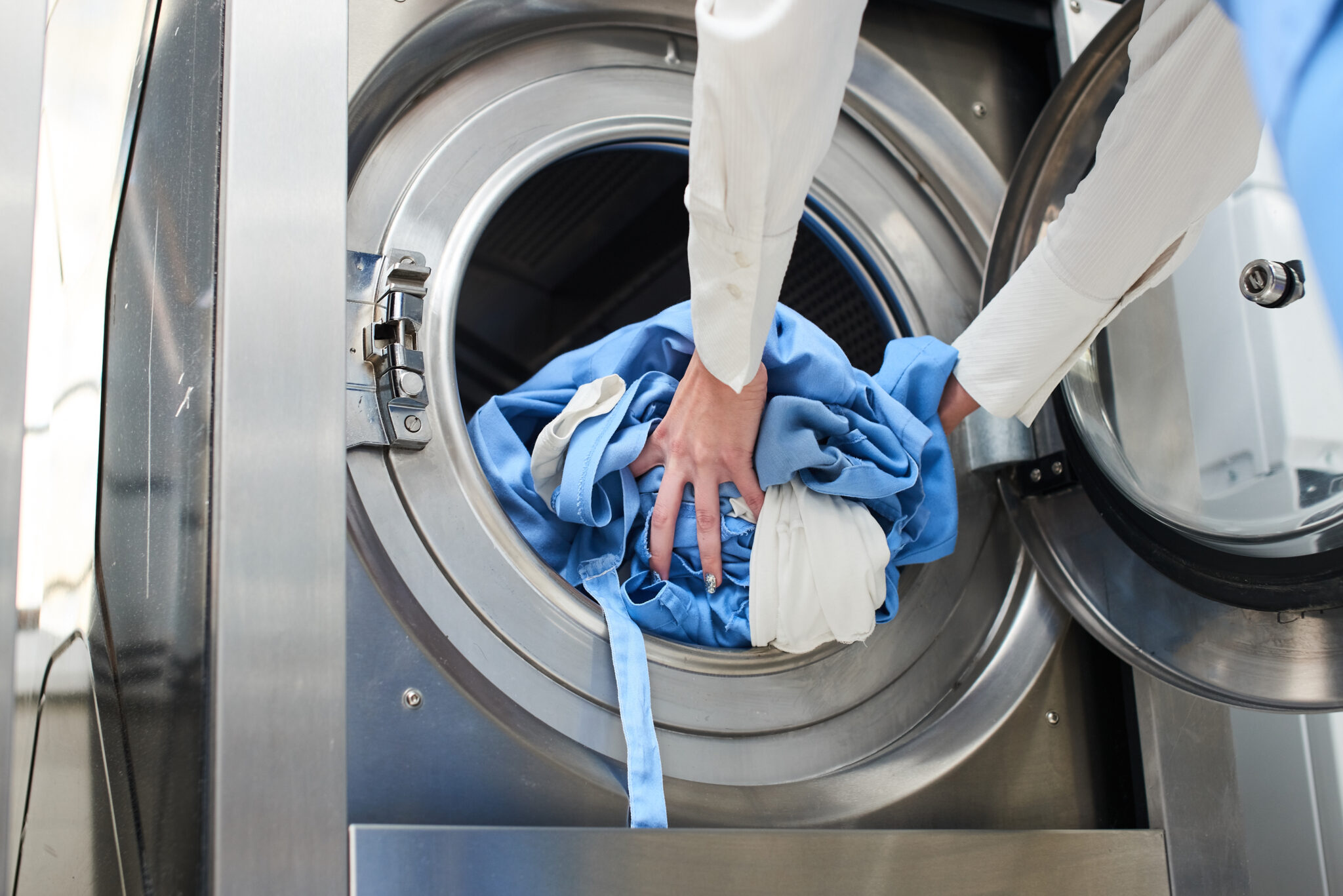 Main chargeant du linge dans une machine industrielle