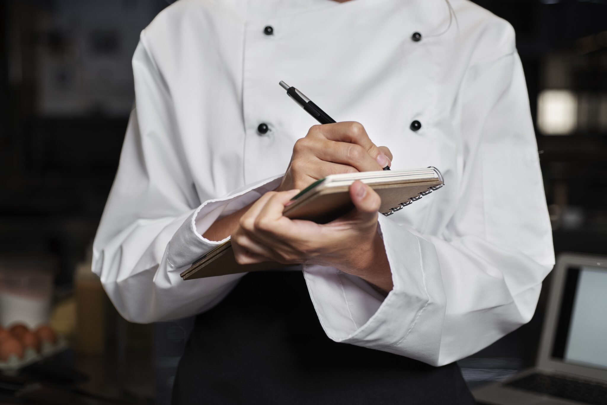 Chef cuisinier écrivant des notes dans une cuisine.