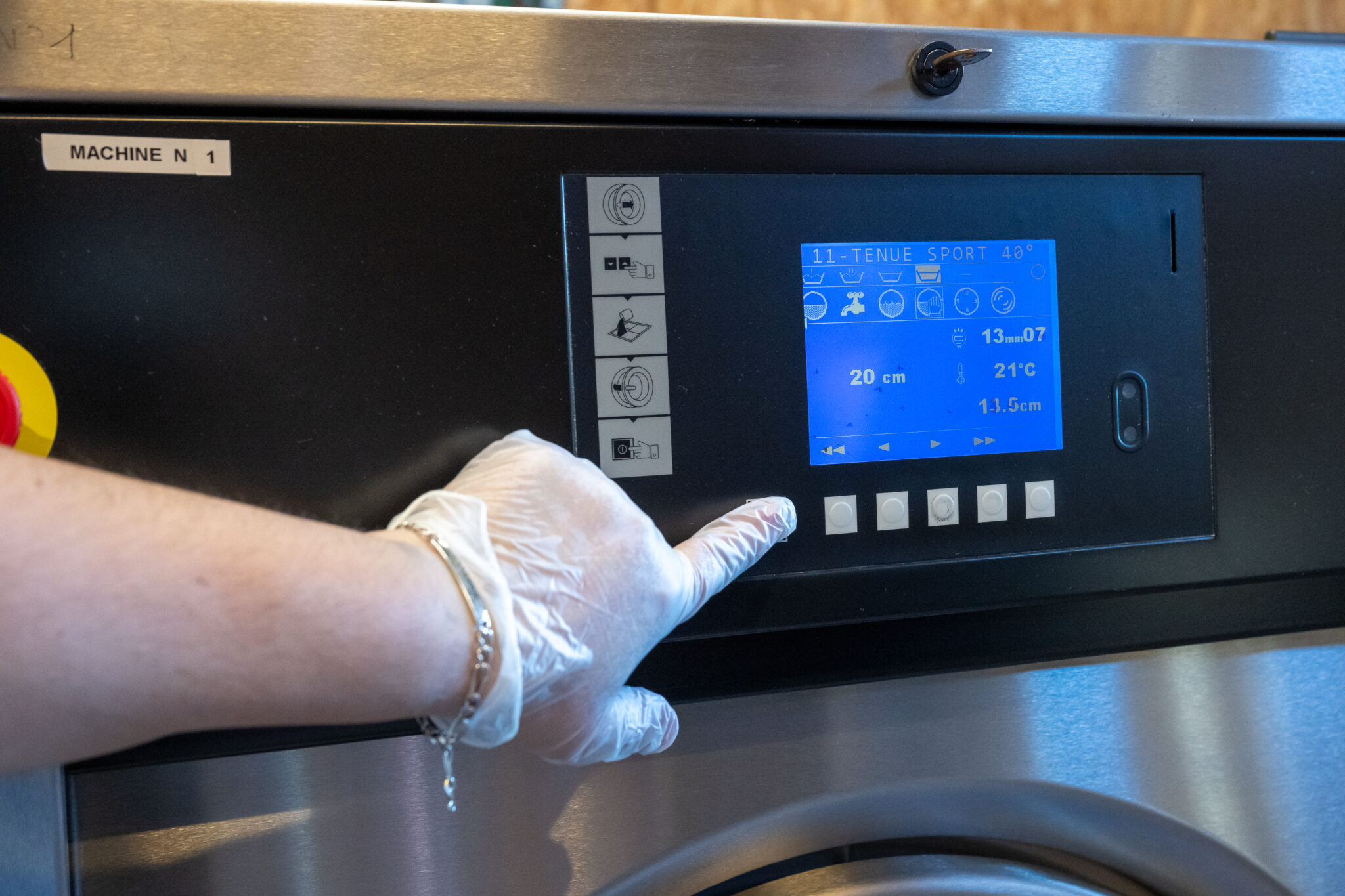 Main réglant une machine à laver industrielle.